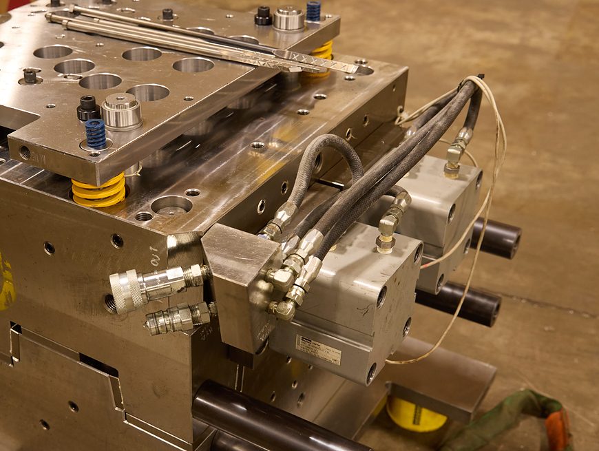 Injection mold with hydraulic core-pull cylinders, hoses and quick couplings, staged on the shop floor